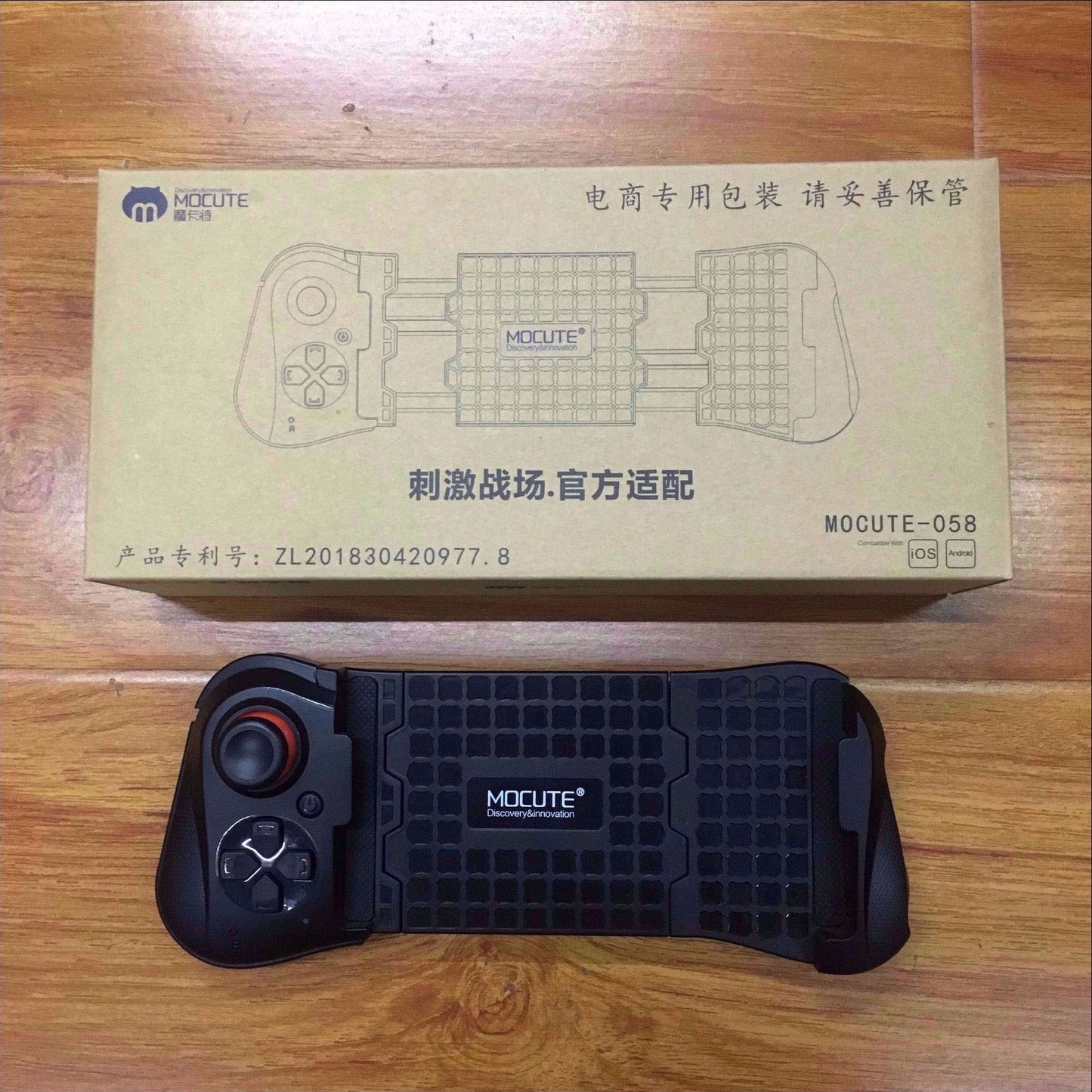 MOCUTE 058 black mobile game controller with joystick and buttons on wooden floor with packaging box