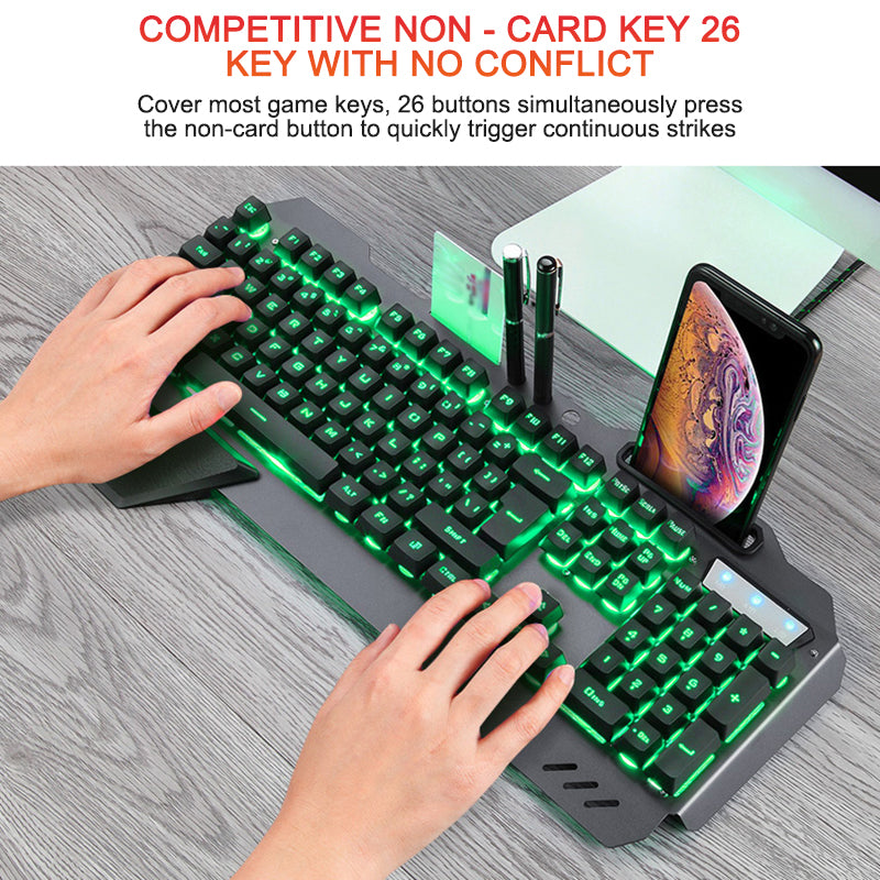 Hands typing on black mechanical gaming keyboard with green backlight and phone holder on wooden desk
