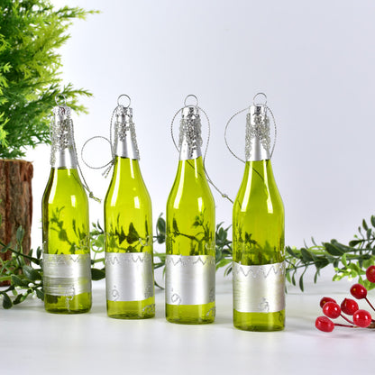 Four green glass bottle Christmas ornaments with silver caps and decorative loops on white surface with greenery and red berries