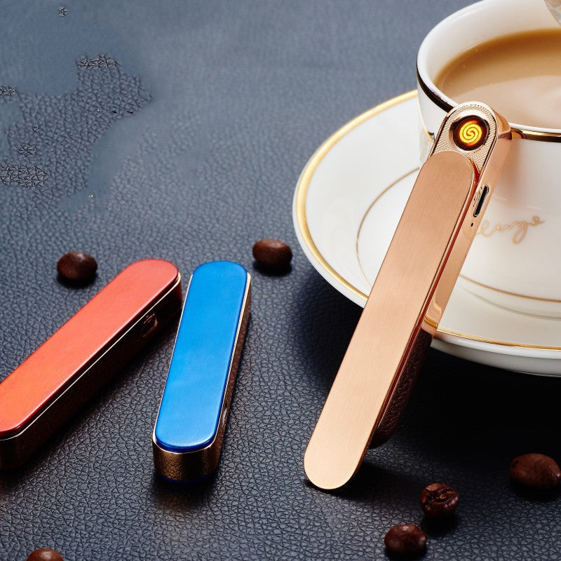 Sleek rose gold electronic lighter glowing near a coffee cup with blue and red lighters on a dark textured surface