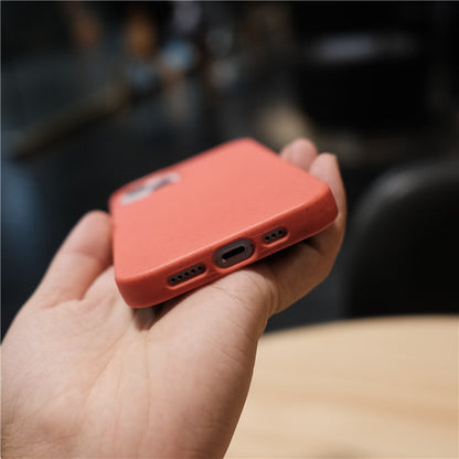 Hand holding smartphone with red protective case on wooden table background