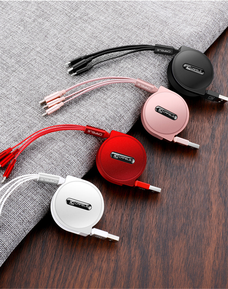 Four retractable multi-port charging cables in black, pink, red, and white on fabric and wood surface