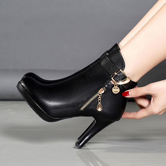 Stylish black leather ankle boots with gold zipper and buckle detail on model's feet