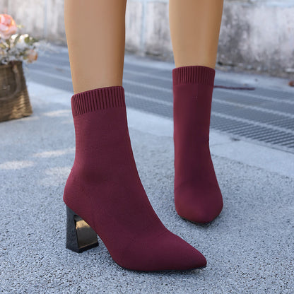 Women's burgundy sock boots with block heels worn outdoors on textured gray pavement