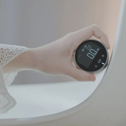 Hand holding a round digital device with a black screen displaying 0.0 in a soft white and beige setting