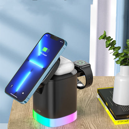 Black wireless charging station on wooden table charging smartphone, earbuds case, and smartwatch