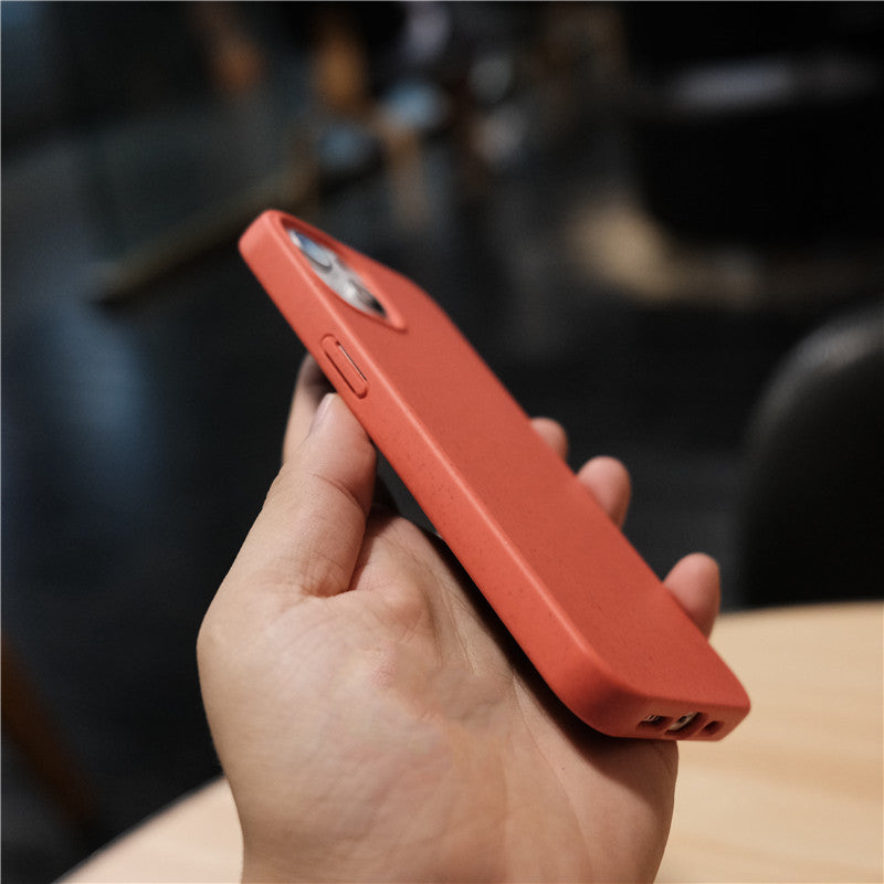 Hand holding a smartphone with a red protective case in a blurred indoor setting