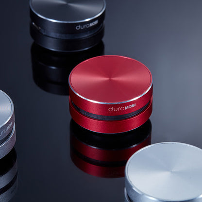Red DuraMobi portable Bluetooth speaker with silver edge on reflective black surface