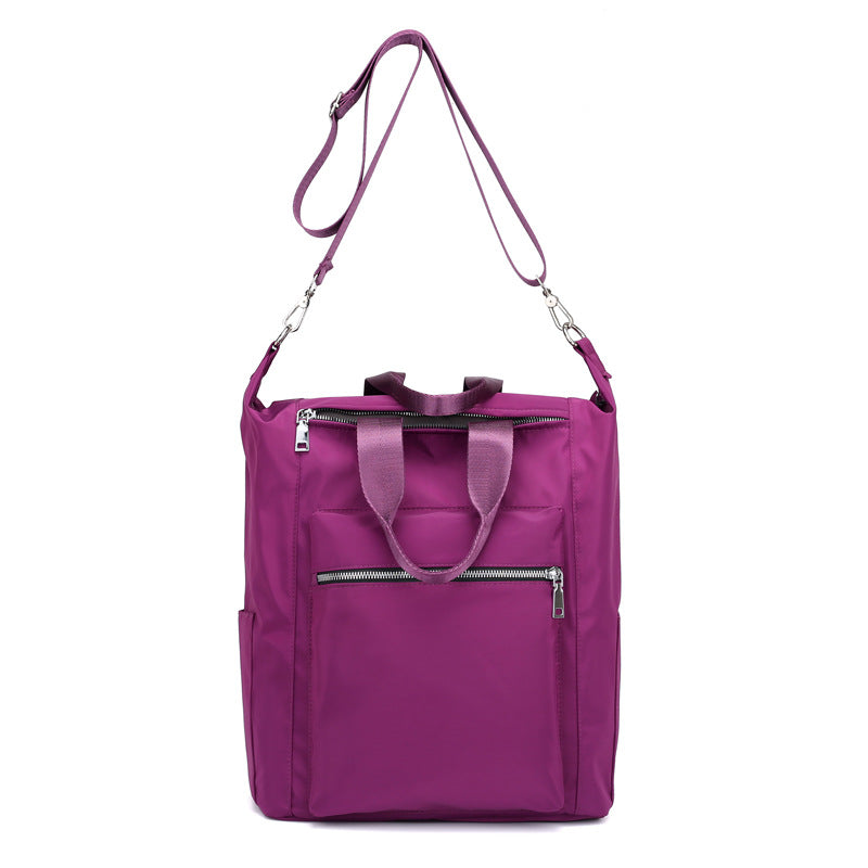 Purple nylon tote bag with dual handles, adjustable shoulder strap, and front zippered pockets