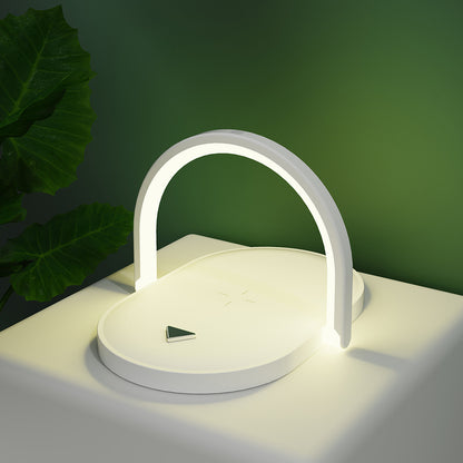 Modern white LED desk lamp with circular base and arch light on white table beside green plant