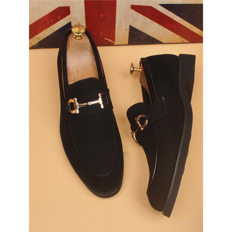 Black men's suede loafers with gold metal buckle detail on beige surface featuring partial Union Jack background