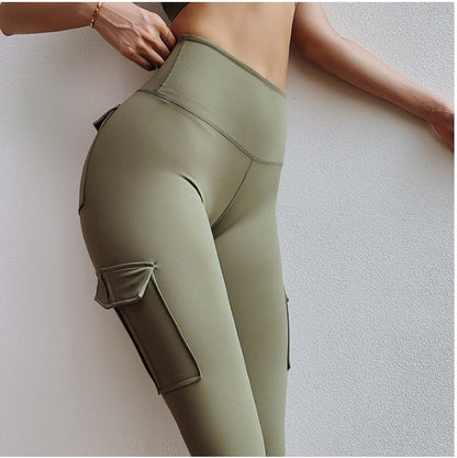 Close-up of woman wearing high-waisted olive green cargo leggings with side pockets against white wall