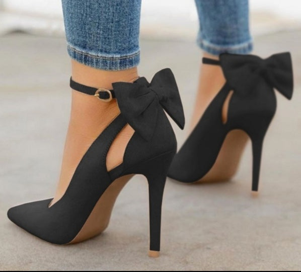 Black high heel shoes with ankle strap and large bow detail worn with blue denim jeans