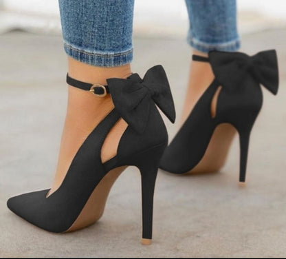 Black high heel shoes with ankle strap and large bow detail worn with blue denim jeans