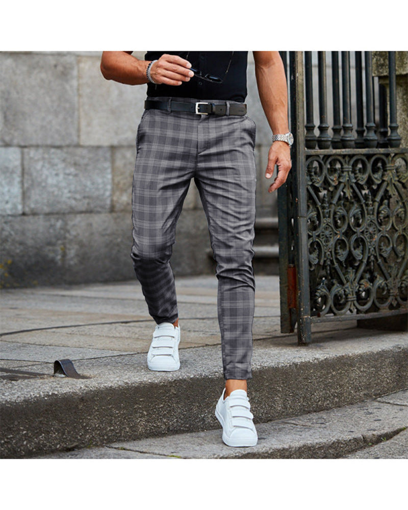 Man wearing gray plaid pants, black belt, white sneakers, and black shirt walking on stone steps