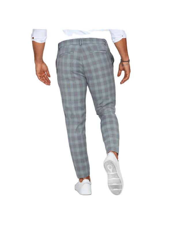Man wearing gray plaid slim fit trousers and white sneakers walking away on white background