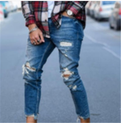 close-up of person wearing ripped blue jeans and a red plaid shirt on a city street