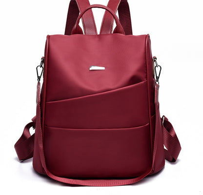 Stylish maroon nylon backpack with adjustable straps, front pockets, and silver clasp detail