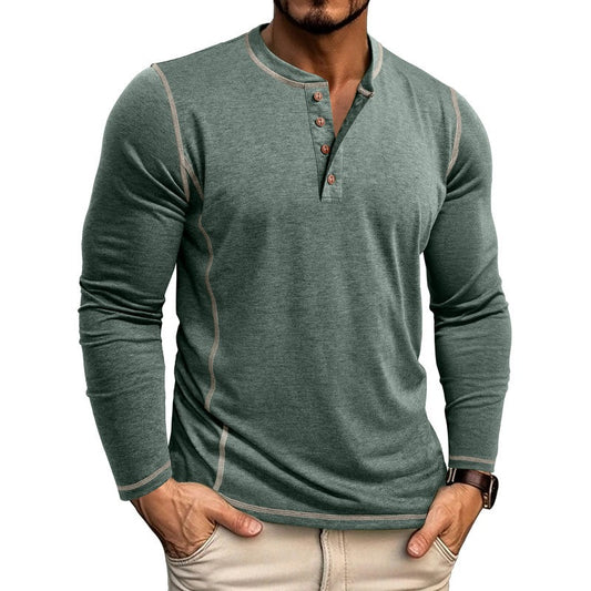Man wearing casual green henley long sleeve shirt with beige stitching and buttons, hands in pockets
