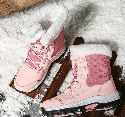Pink winter boots with white fur lining on wooden slats in snow background