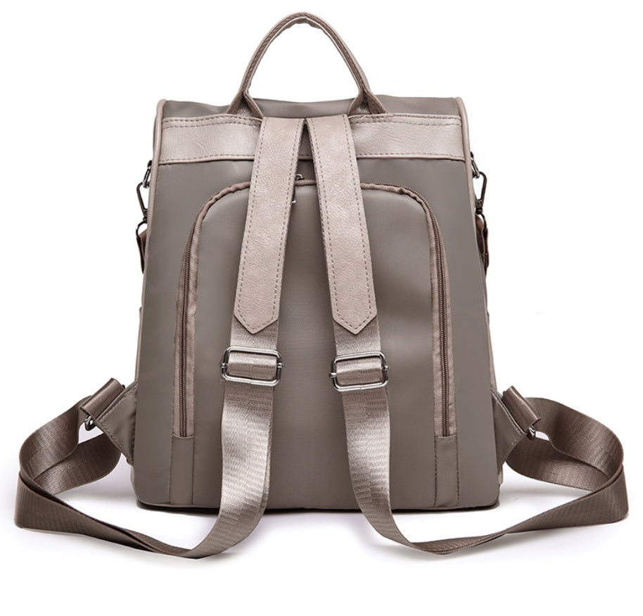 Stylish taupe square backpack with adjustable straps and dual zippers on white background