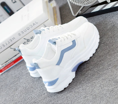 white fashion sneakers with light blue accents on gray carpet near books and fan