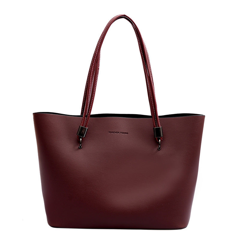 Maroon leather tote bag with double handles and 'Forever Young' logo on front