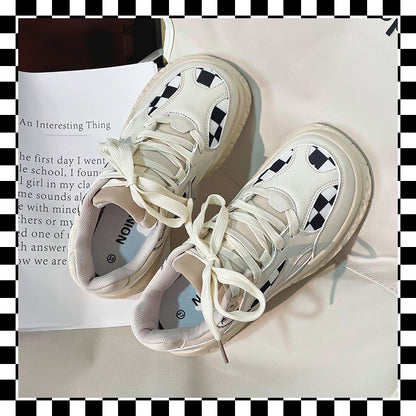 White chunky sneakers with black and white checkerboard pattern, beige padded tongue, white laces