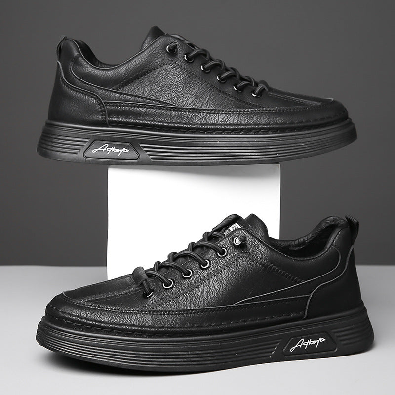 Pair of black leather casual sneakers with textured upper and signature logo on sole against gray background