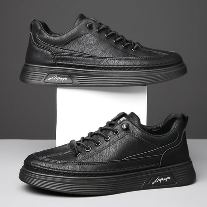 Pair of black leather casual sneakers with textured upper and signature logo on sole against gray background