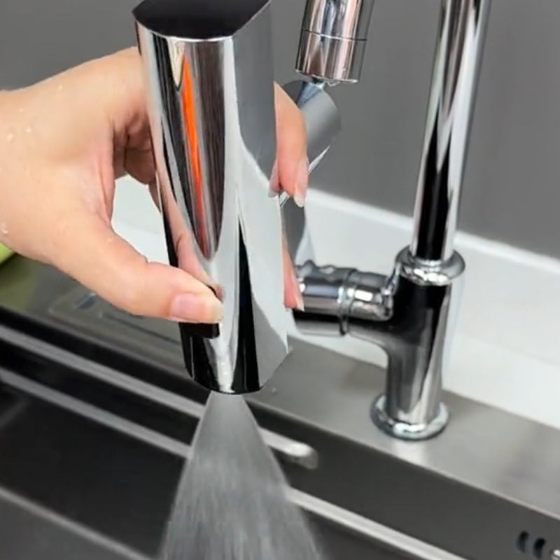 Hand holding a detachable chrome kitchen faucet sprayer over a stainless steel sink