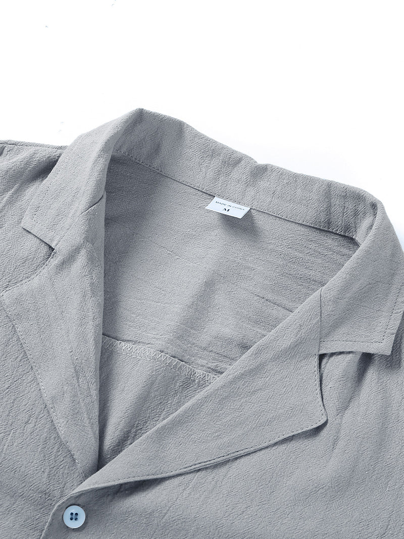 Close-up of light gray textured shirt collar with medium size label and white button detail