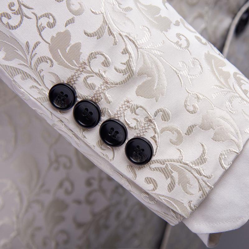 White brocade jacket sleeve with intricate floral pattern and four black buttons