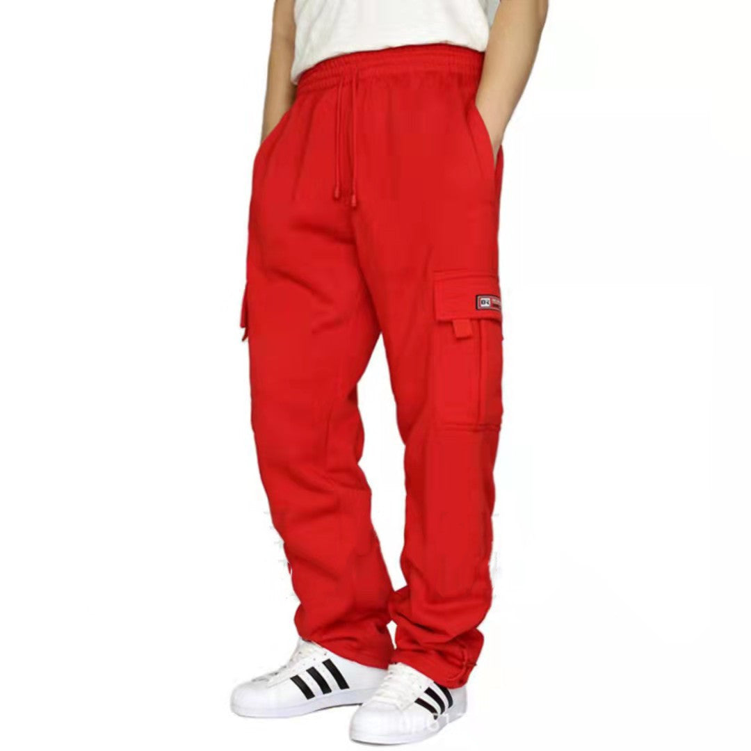 Person wearing bright red cargo pants with pockets and white Adidas sneakers with black stripes