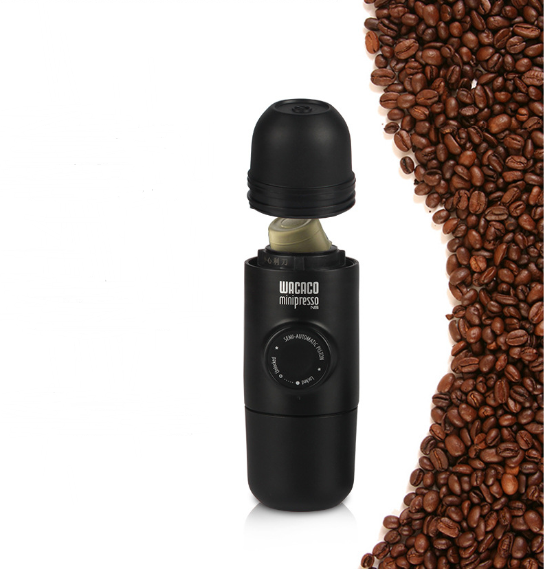 Wacaco Minipresso portable espresso machine with black finish next to coffee beans