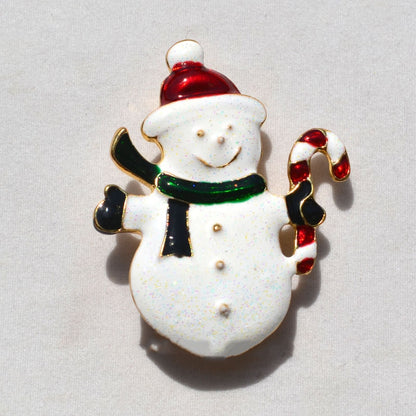 festive snowman pin with red Santa hat, green scarf, black mittens, holding a red and white candy cane