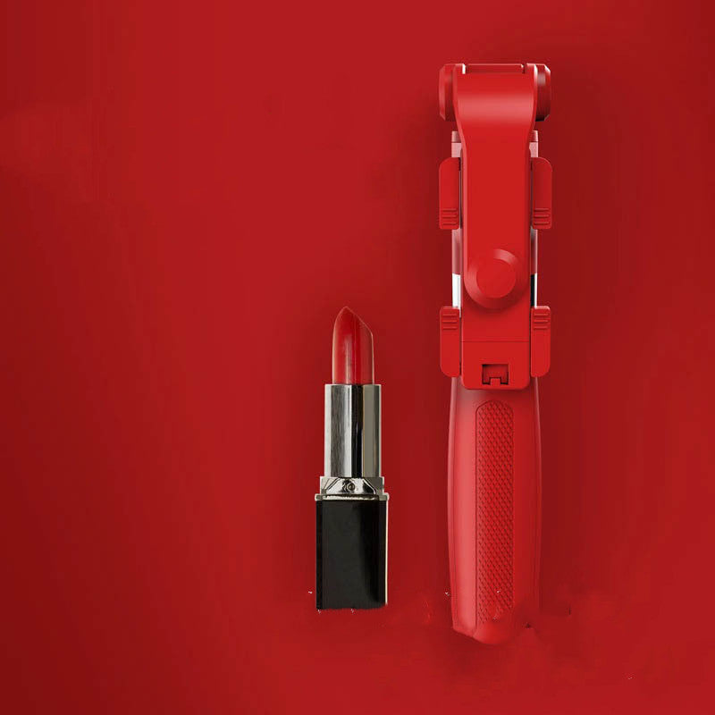 Red lipstick and matching red handheld device on a vibrant red background