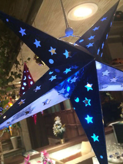 Blue illuminated star-shaped hanging lantern with star and moon cutouts in indoor festive setting
