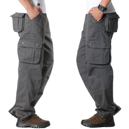 Men's gray cargo pants with multiple pockets worn with brown hiking shoes and white t-shirt