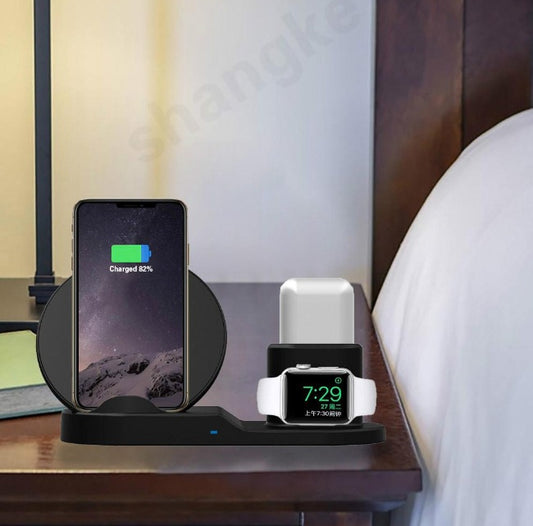 Black wireless charging station on bedside table charging smartphone, smartwatch, and wireless earbuds case