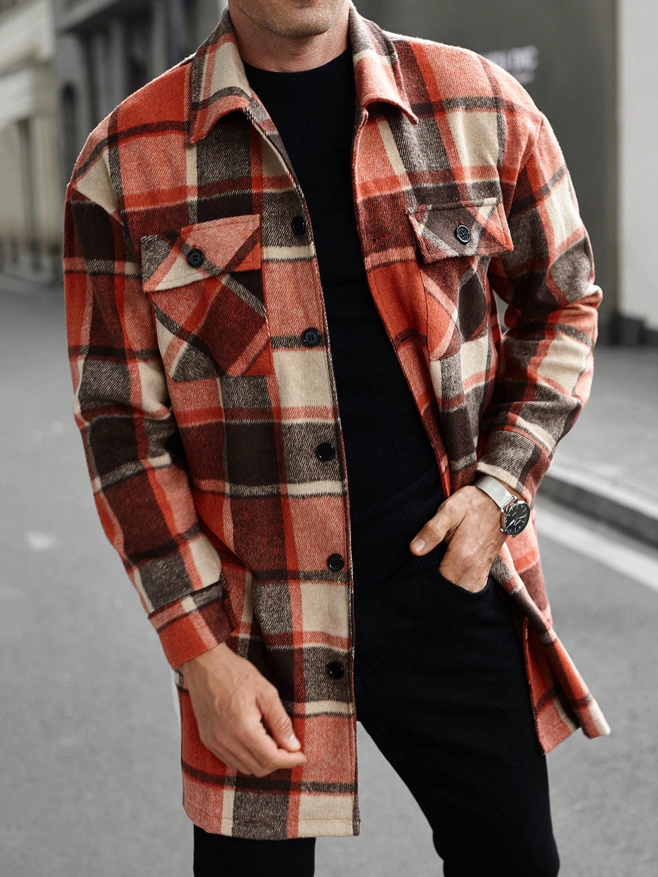 Man wearing a stylish orange and brown plaid button-up jacket with black inner shirt and watch