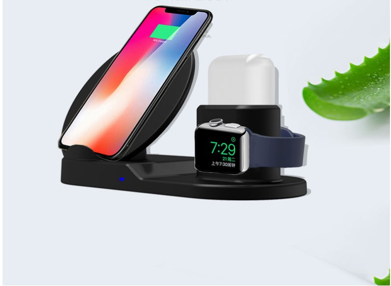 Black wireless charging station with smartphone, smartwatch, and earbuds case on white background with aloe leaf