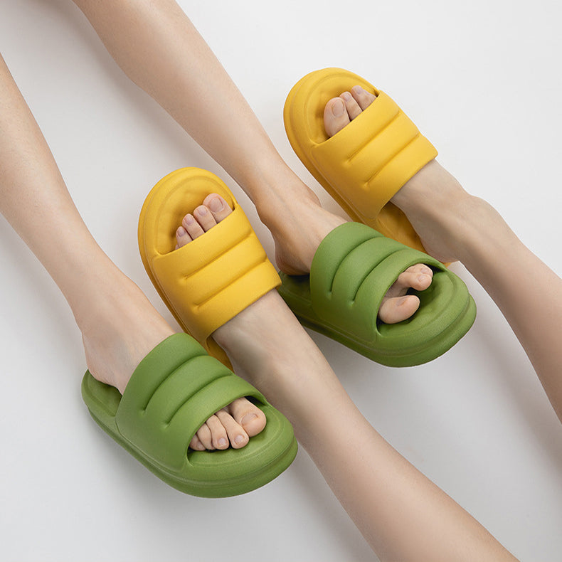 Two pairs of feet wearing yellow and green cushioned slide sandals on white background