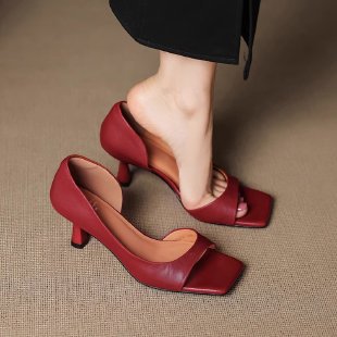 Woman wearing stylish red kitten heel sandals with square toe, alongside a matching pair on beige carpet