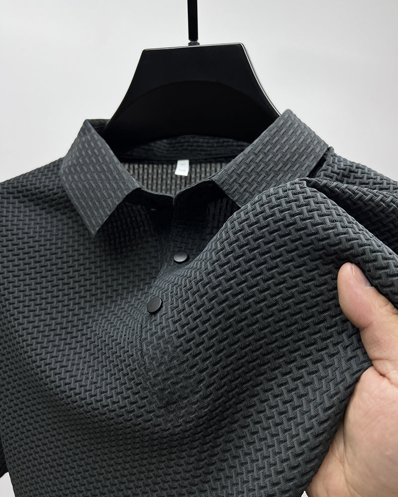 Close-up of a black textured polo shirt with woven pattern and black buttons held by a hand