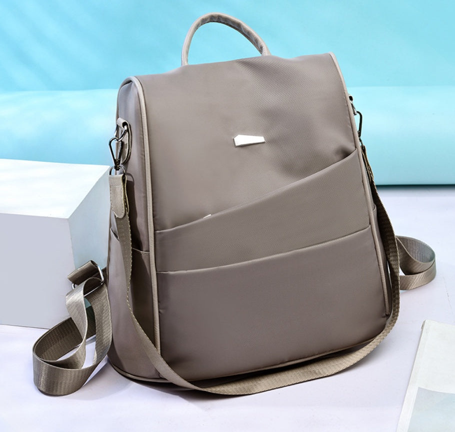 Grey nylon crossbody bag with front pockets and adjustable strap on light background