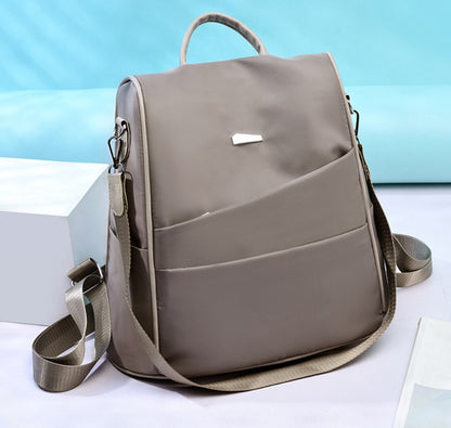 Grey nylon crossbody bag with front pockets and adjustable strap on light background