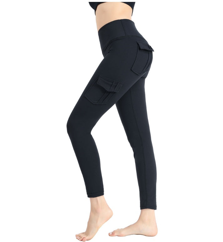 Woman wearing black high-waisted cargo pocket leggings in side view, barefoot on white background