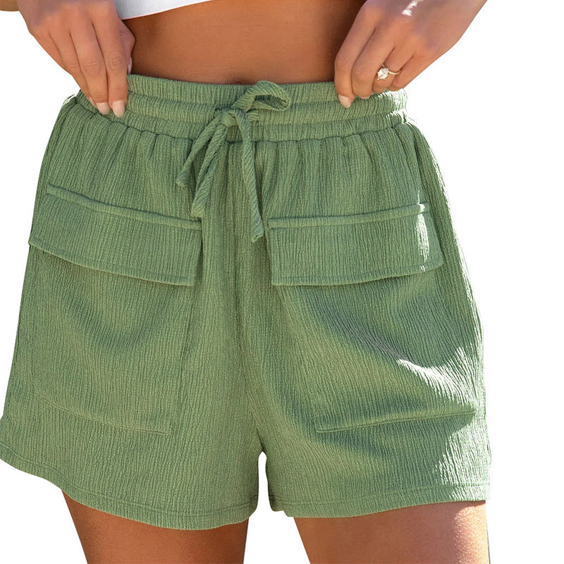 Woman wearing green textured drawstring shorts with large front flap pockets