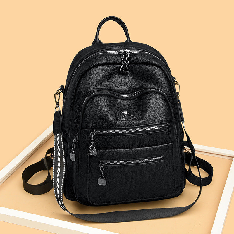 Black leather backpack with multiple zipper pockets and adjustable straps on beige background